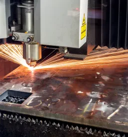 Laserski stroj natančno reže jekleno pločevino, pri čemer ustvarja svetleče iskre. To je ključna faza v industrijskem procesu obdelave kovin.