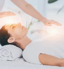 Ženska z zaprtimi očmi prejema reiki terapijo. Išče energijsko podporo za notranje ravnovesje telesa Jesenice.