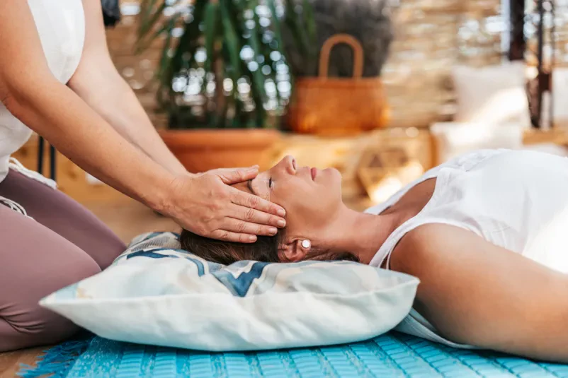 Ženska se sprošča med reiki terapijo, ki prinaša energijsko podporo za notranje ravnovesje telesa Jesenice.