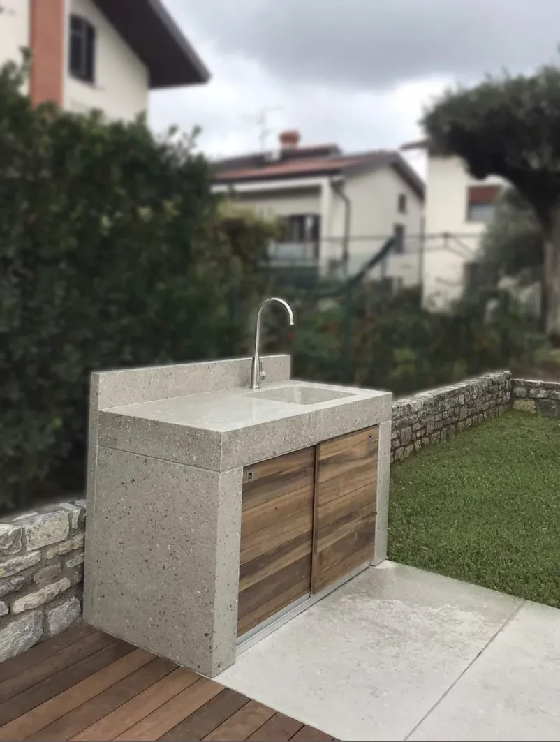 Vertikalni pogled na betonsko kuhinjo Prikaz moderne zunanje kuhinje z betonskimi pulti, vgrajenim umivalnikom in funkcionalnim prostorom za delo.