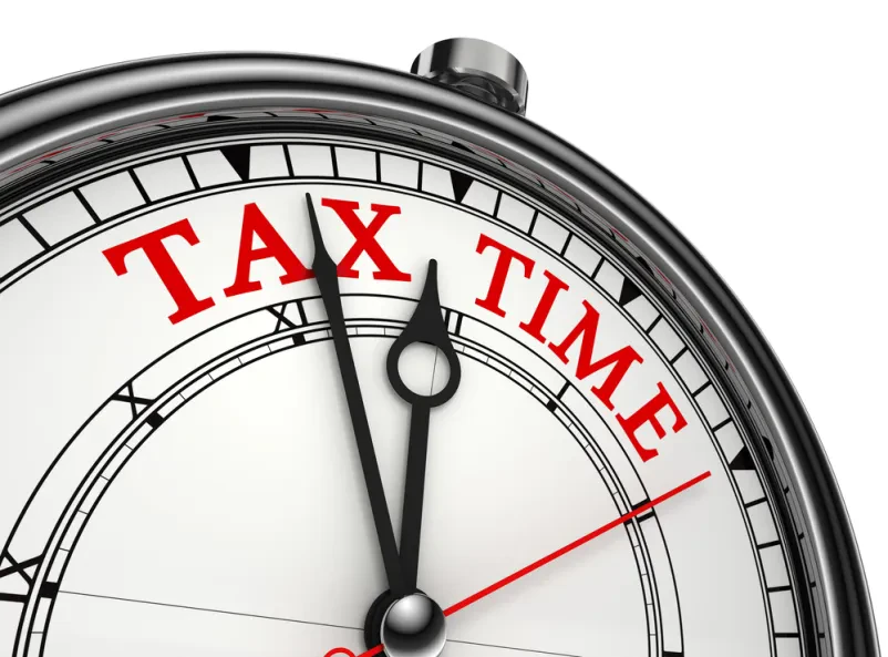 Čas za davčne obveznosti Povečava konceptne ure, ki prikazuje besedo »TAX« (davek), spominja na pomembnost pravočasne ureditve finančnih zadev.
