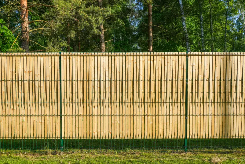 Mrežasta ograja z lesenimi letvicami za zasebnost Montaža panelnih ograj Krško, Dolenjska: Trajna ograja z zelenimi varjenimi mrežastimi paneli in vgrajenimi lesenimi letvicami, ki zagotavlja zasebnost ob urejenem posestvu.