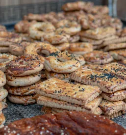 Okrogel, sveže pečen kruh z začimbami, postrežen na leseni deski, ki vabi s svojo hrustljavo skorjico.