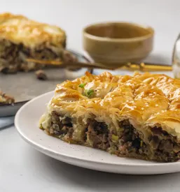 Zvit, slan burek z nadevom iz mesa in gob, bogato posut s sezamovimi semeni, ponudba za ljubitelje pekovskih izdelkov.