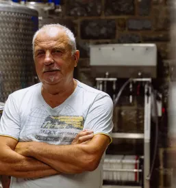 Portret Walterja Miklavčiča, spoštovanega lokalnega pridelovalca, ki s ponosom nadaljuje družinsko tradicijo v vinogradništvu.