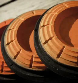 Bližnji posnetek kupa svetlo oranžnih glinastih tarč, pripravljenih za metanje, ki se uporabljajo pri športnem streljanju s šibrenico.