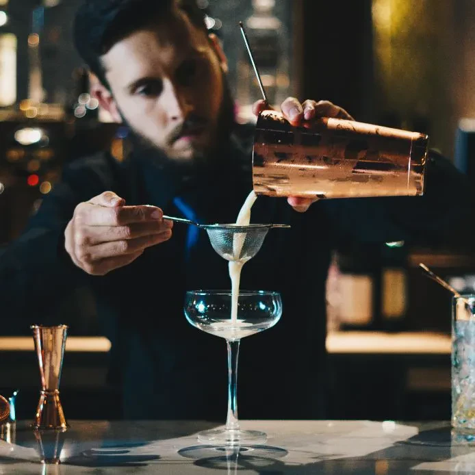 Mladi barmen s ponosom pripravlja koktajl. Prikazuje praktično znanje gastronomije v Strokovni izobraževalni center Celje.
