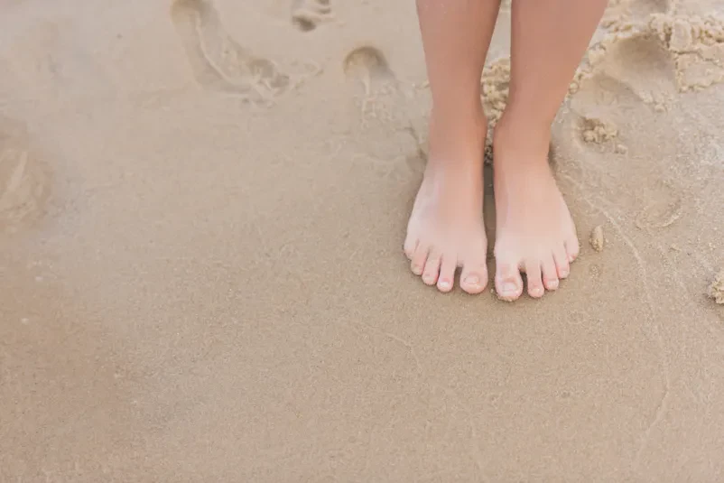 Otrok sam na prostrani peščeni plaži ob morju Otrok stoji na peščeni plaži ob morju. Ta prizor prikazuje mirne družinske počitnice in brezskrbno otroštvo, idealno za nastanitev blizu obale.
