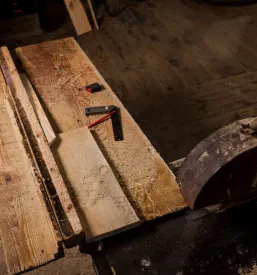 Pogled od zgoraj na delovno mizo z veliko strojno žago v žagi, pripravljeni za obdelavo lesa, kar poudarja industrijski vidik razreza in priprave lesa.