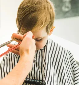 Frizerska striže otroku lase v frizerskem salonu