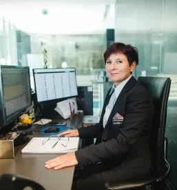 Prijazna varnostnica na recepciji sodobne poslovne stavbe pričaka obiskovalce, hkrati pa zagotavlja nadzor in varnost. Pomemben del varnostnega sistema.