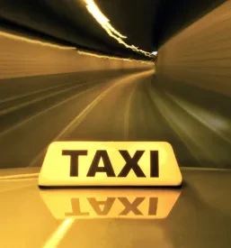 Rumeni taksi drvi skozi osvetljen tunel, kar simbolizira hitrost in učinkovitost prevoza oseb. Idealna izbira za Hiter taksi Ljubljana.