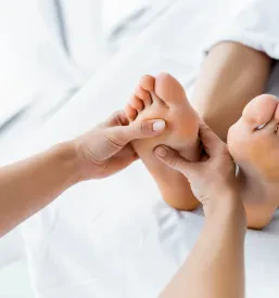 Masseurka izvaja sproščujočo masažo stopal v spa okolju, obdana s prijetno svetlobo. Ta masaža ponuja globoko sprostitev in je del kvalitetne refleksoterapije Vič Ljubljana.