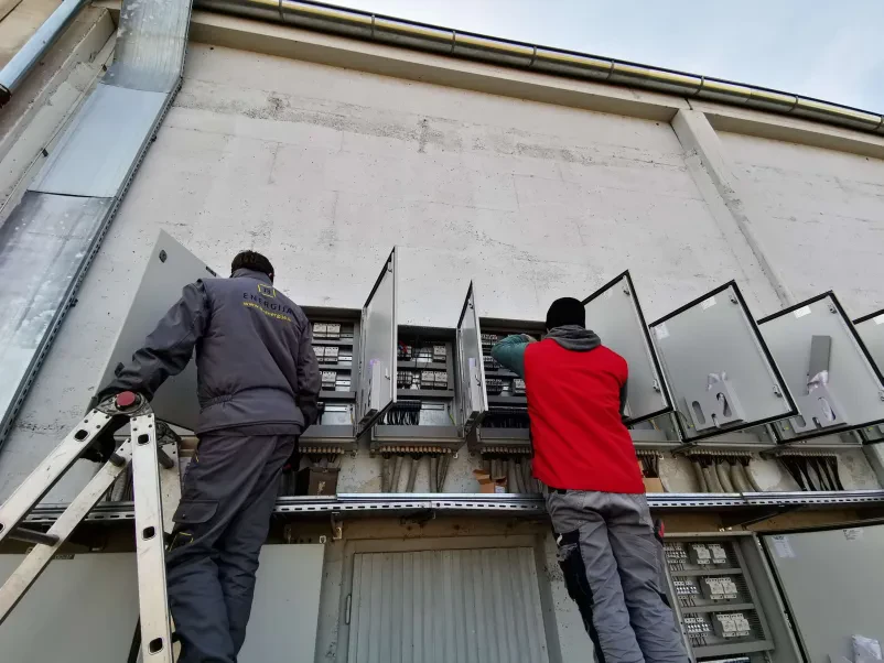Velika sončna elektrarna na strehi podjetja Velika sončna elektrarna na strehi industrijskega objekta, monterji na delu. Montaža sončnih elektrarn Slovenija za poslovne uporabnike.