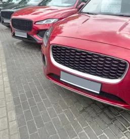 Dolga vrsta svetlih luksuznih vozil, parkiranih na prostem, pričakuje svoje nove lastnike v sklopu ponudbe prodaje vozil na avto-placu.