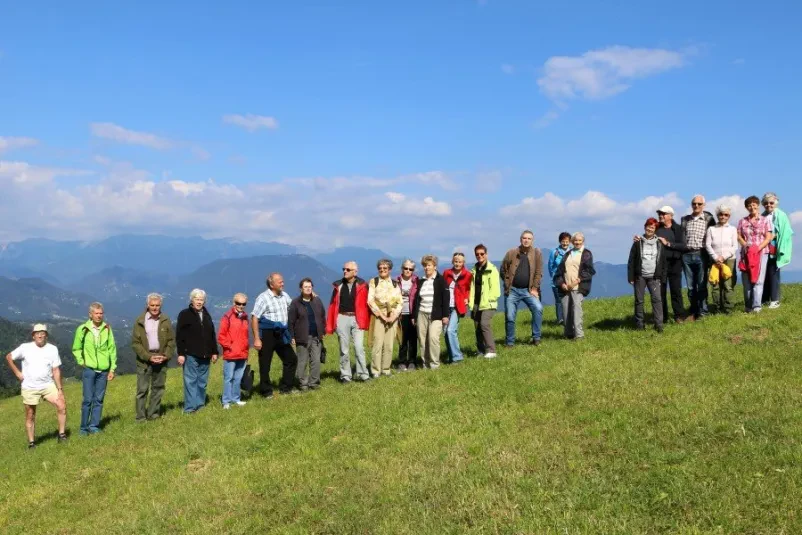 Ženska pregleduje arhivsko gradivo Ženska se posveča pregledu starih fotografij in dokumentov na mizi v arhivski sobi, skrbno razvršča gradivo.