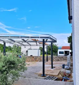 Delavec skrbno pregleduje sveže pobarvane kovinske izdelke, kar poudarja natančnost našega prašnega barvanja in lakiranja.