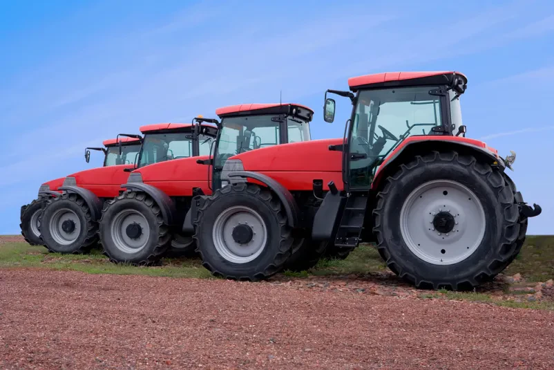 Sodoben traktor na polju ob sončnem dnevu Zmogljiv traktor v zelenem polju pod vedrim modrim nebom, ki prikazuje sodobno kmetijsko mehanizacijo v uporabi.
