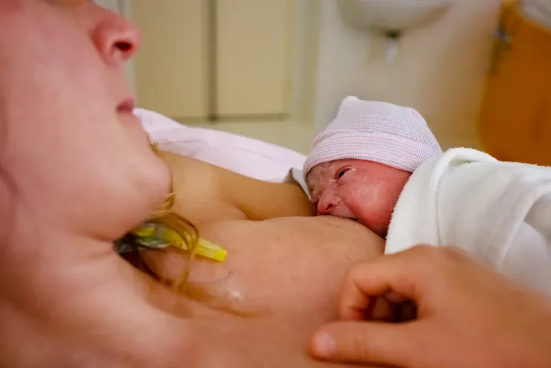 Nežen dotik matere in dojenčka Od blizu posnetek mamice, ki z ljubeznijo boža drobna stopalca svojega dojenčka, poudarja občutljivo nego in skrb.