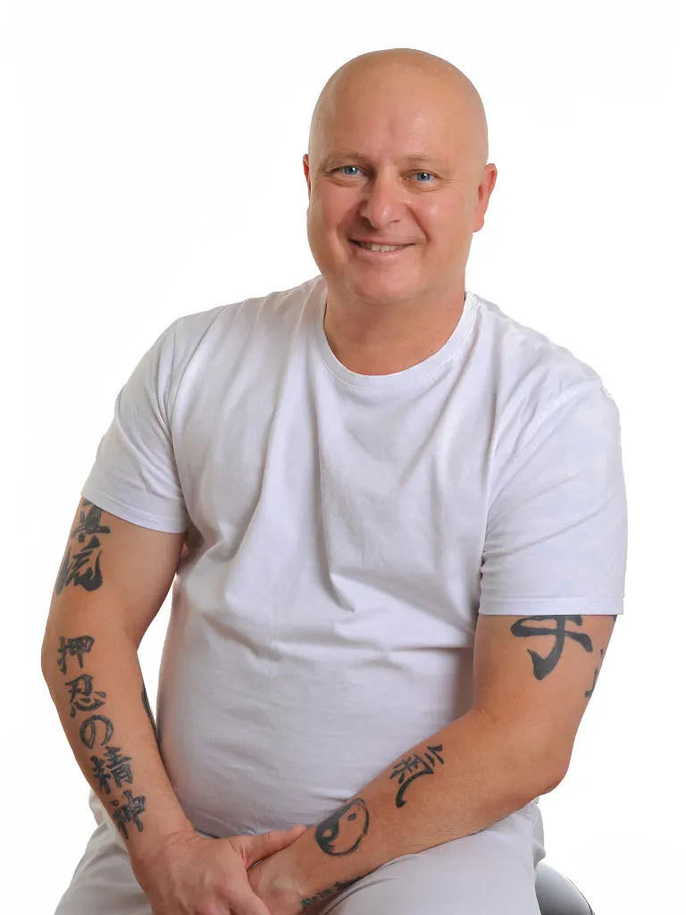 Prijazen in profesionalen terapevt s toplim nasmehom, pripravljen na izvajanje terapevtskih masaž in drugih storitev.