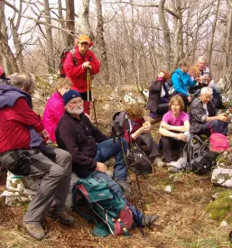 Skupina veselih planincev pozira na vrhu Debelega vrha (864 m) v Beli Krajini, s prelepim razgledom in občutkom izpolnitve.