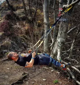 Trener z dvignjeno roko izvaja počep skupaj s športniki