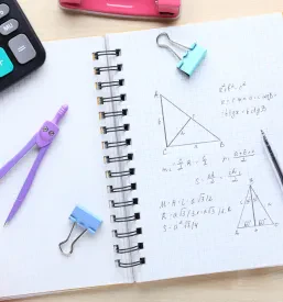 Zvezek s šestilom in kalkulatorjem, ki jih uporabljajo študentje fizike in matematike na inštrukcijah.