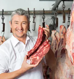 Mesar pri delu v mesnici v Zrečah pripravlja sveže kose mesa ter skrbi za urejeno ponudbo v mesnici.