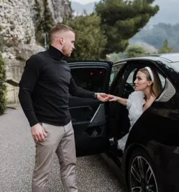 Najem prevoza z avtomobilom za poroka, ženin in nevesta izstopata iz črnega avtomobila.