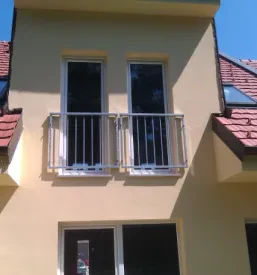 Francoski balkon z inox ograjo na hiši z rumeno fasado