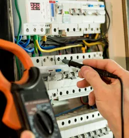 Preverjanje električne napetosti v elektro omarici z varovalkami.