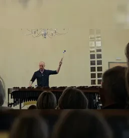 Glasbenik stoji pred občinstvom in igra na marimbo