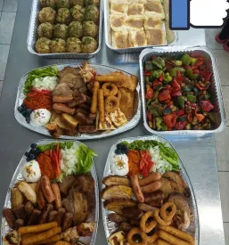 Izbor sveže pripravljenih jedi za catering v Osrednji Sloveniji, postavljen na pladnje na mizi.