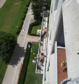 Višinski delavec med sanacijo zunanjega dela objekta uporablja profesionalno delovno opremo.
