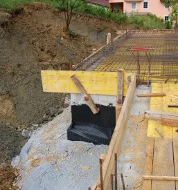 Gradbišče, kjer poteka gradnja enodružinske hiše, delavci so z rumenimi lesenimi deskami pripravili površino za betoniranje.