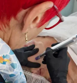 Kozmetičarka s sodobnimi aparaturami izvaja nego kože na stranki v kozmetičnem salonu v Ljubljani.