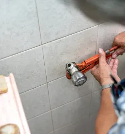 Oprema za izvajanje strojnih inštalacij, ki jo v rokah nosi vodovodar.