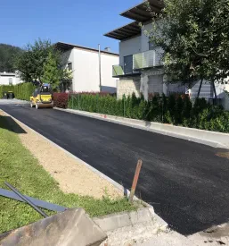 Rdeč kamion prevaža material po dovozni cesti, kje poteka urejanje in priprava terena pred asfaltiranjem v Osrednji Sloveniji-