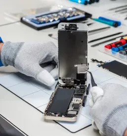 Zaposleni z orodjem popravlja pokvarjen mobilni telefon v Murski Soboti.