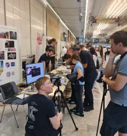 Predstavitev študija fizike na stojnici v Ljubljani, kjer študent govori z otrokom.