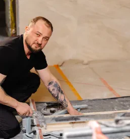 Delavec izvaja adaptacijska dela v starejši kopalnici na Koroškem, kjer poteka menjava keramike na tleh in stenah.