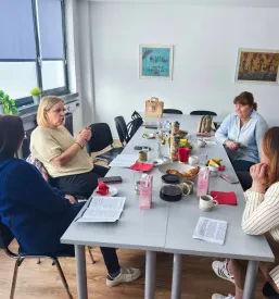 Slika zaposlenih, ki izvajajo poklicno rehabilitacijo, ki sedijo za mizo na sestanku.