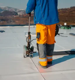 Detajl polaganja hidroizolacijske membrane na gradbišču, ki preprečuje vdor vode in zagotavlja učinkovito zaščito strešne konstrukcije.