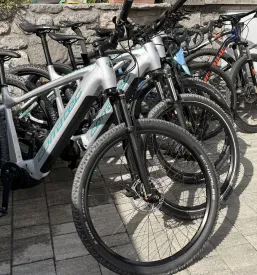 Detajl električnega gorskega kolesa z robustnimi pnevmatikami in vzmetenjem, popolnega za raziskovanje kraške narave.