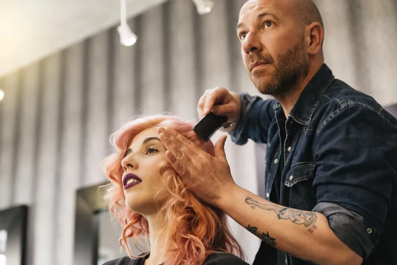 Mladostna ženska z urejenimi lasmi uživa v kakovostnem striženju pri frizerki, kar je značilno za Kvalitetni frizerski salon Šmarje pri Jelšah.