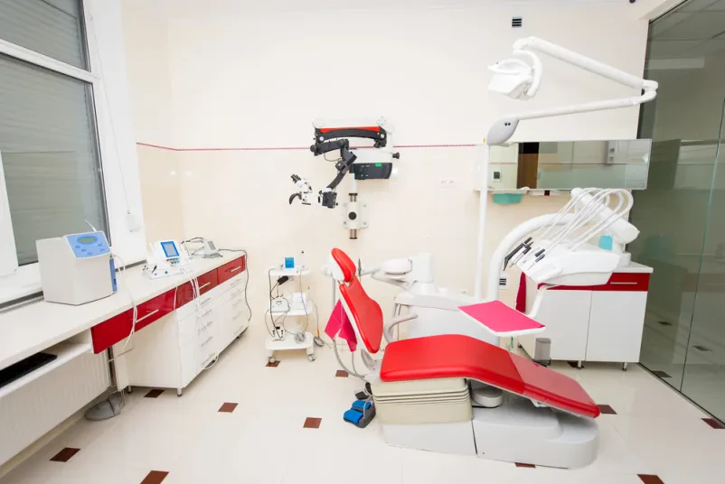 Rdeč zobozdravniški stol v sodobni ordinaciji Notranjost zobozdravstvene ordinacije z izrazitim rdečim stolom in napredno medicinsko opremo, ki ponuja zasebno splošno samoplačniško zobozdravstvo Maribor.