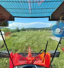 Traktor je parkiran na dvorišču podjetja, ki se ukvarja s prodajo in servisiranjem kmetijskih strojev.