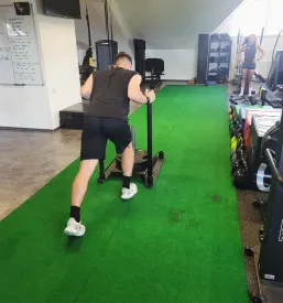 Član fitnesa vadi na zeleni podlagi s fitnes opremo na Savinjskem.
