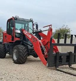 Pogled na kmetijski traktor, parkiran pred objektom za prodajo in servis kmetijske mehanizacije.