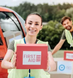 Ženska v rokah drži paket s produkti za prvo pomoč ponesrečencem.